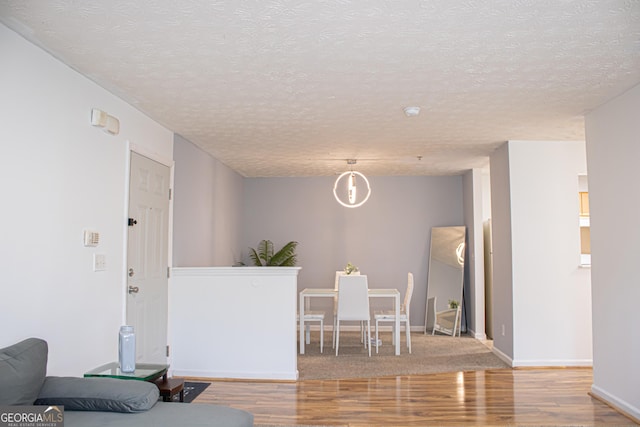 interior space with a textured ceiling, baseboards, and wood finished floors