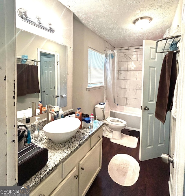bathroom with wood finished floors, a textured ceiling, vanity, toilet, and shower / bath combo with shower curtain