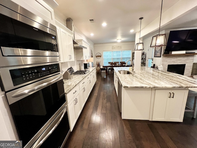 kitchen featuring a large island, white cabinets, visible vents, stainless steel appliances, and a sink