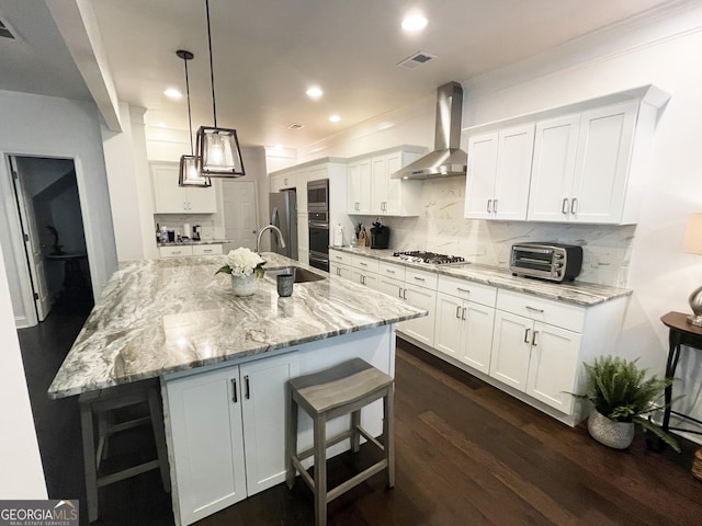 kitchen featuring visible vents, wall chimney exhaust hood, a sink, appliances with stainless steel finishes, and white cabinetry