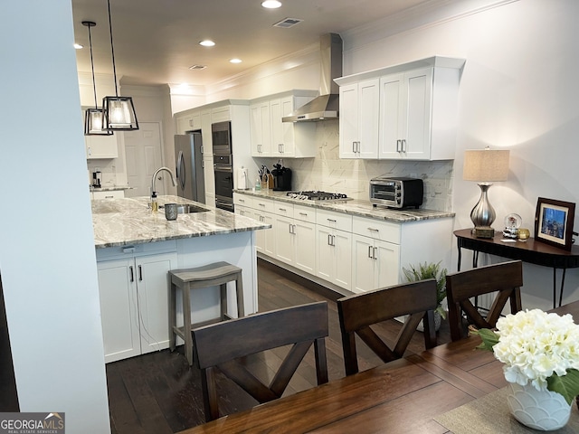 kitchen featuring appliances with stainless steel finishes, a sink, wall chimney range hood, and dark wood-style flooring
