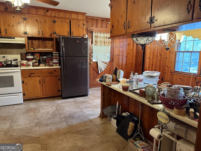 kitchen with brown cabinets, white electric range, under cabinet range hood, and freestanding refrigerator