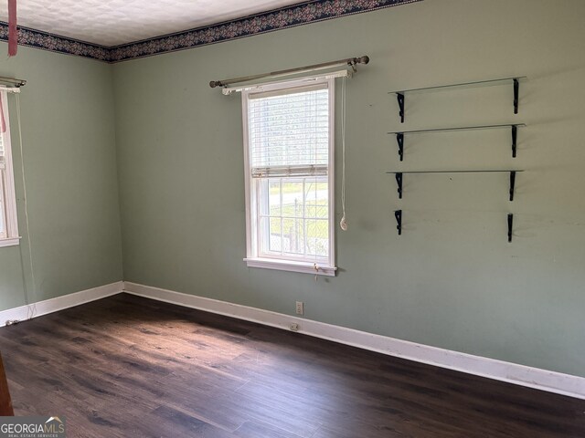 empty room with baseboards and dark wood-style flooring