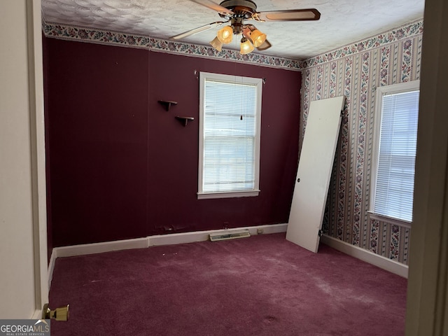 carpeted spare room with baseboards, a textured ceiling, visible vents, and wallpapered walls