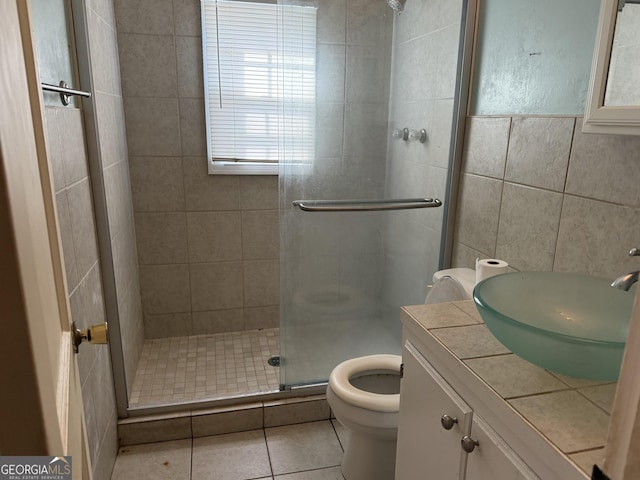 full bath featuring tile patterned flooring, vanity, tile walls, toilet, and a stall shower