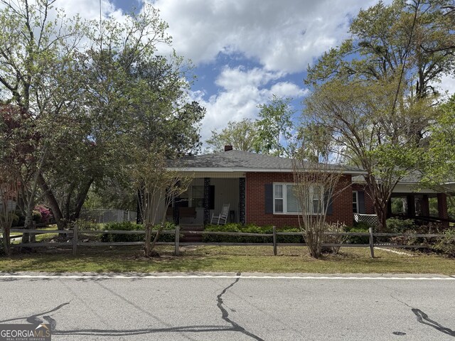 ranch-style house featuring brick siding, a fenced front yard, and a porch