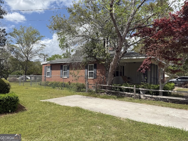 view of front of home featuring brick siding, fence, and a front lawn