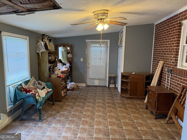 entrance foyer featuring a ceiling fan, brick wall, and a textured ceiling