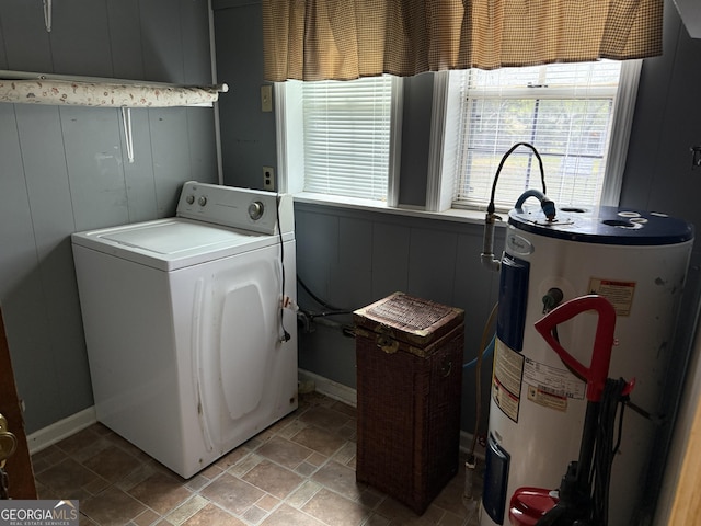washroom with water heater, laundry area, washer / dryer, stone finish floor, and baseboards