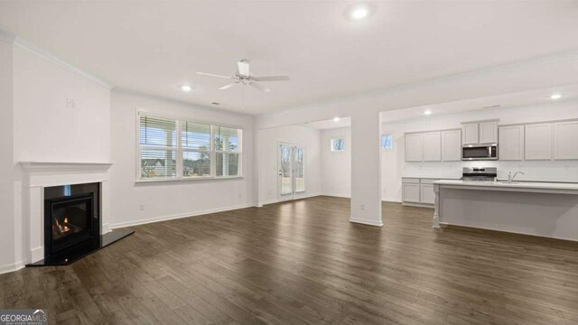 1129 Blue Juniper Cir, Loganville, GA 30052 - unfurnished living room featuring recessed lighting, baseboards, dark wood-style floors, ceiling fan, and a glass covered fireplace