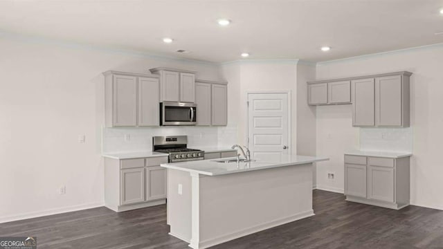 kitchen with appliances with stainless steel finishes, dark wood-type flooring, an island with sink, a sink, and gray cabinets