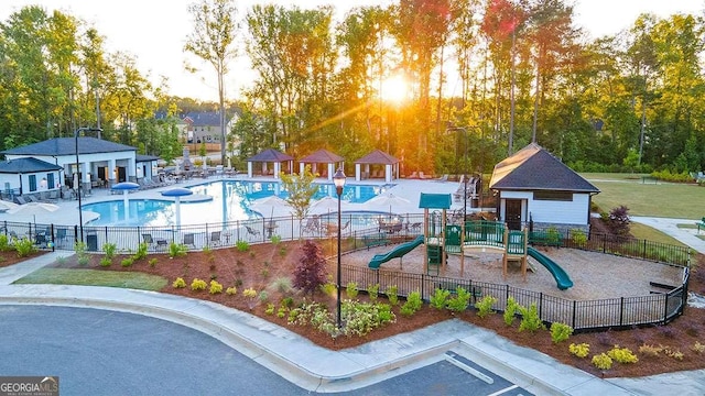 community pool featuring fence, playground community, and a patio area
