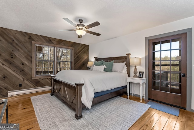 80 Lake Forest Ct, Lakemont, GA 30552 - bedroom featuring baseboard heating, wooden walls, hardwood / wood-style floors, a ceiling fan, and baseboards