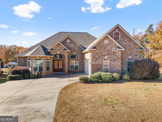 view of front of property featuring driveway, a front yard, an attached garage, brick siding, and a shingled roof