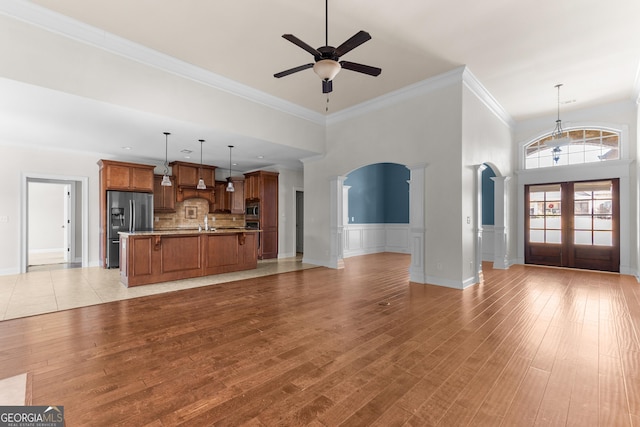 157 Wessex Dr, Bonaire, GA 31005 - unfurnished living room with arched walkways, ceiling fan, french doors, decorative columns, and light wood finished floors