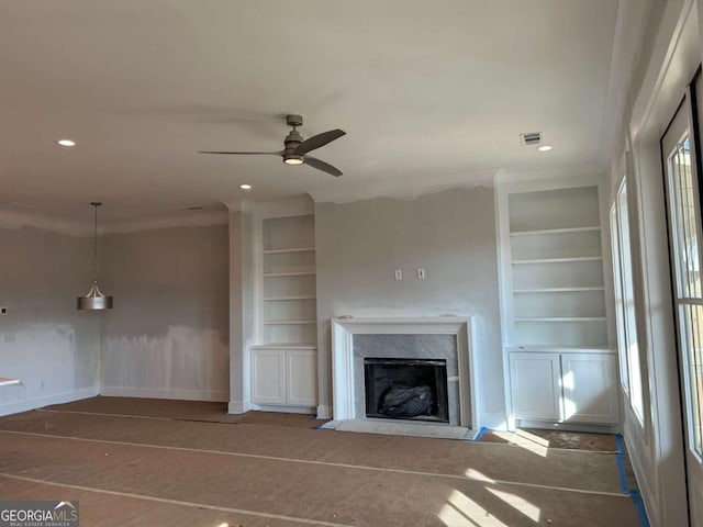 unfurnished living room with a high end fireplace, crown molding, built in shelves, recessed lighting, and a ceiling fan