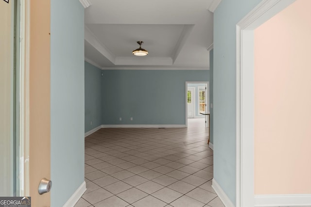 interior space featuring a tray ceiling, light tile patterned flooring, baseboards, and ornamental molding