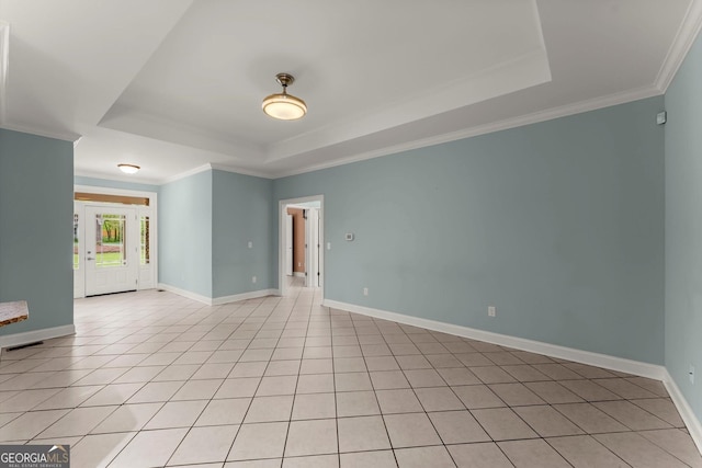 empty room featuring ornamental molding, a tray ceiling, and baseboards