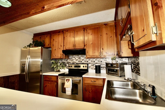 3789 Heatherwoods Dr, Valdosta, GA 31605 - kitchen with light countertops, under cabinet range hood, brown cabinetry, appliances with stainless steel finishes, and a sink