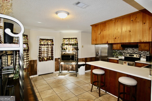 3789 Heatherwoods Dr, Valdosta, GA 31605 - kitchen featuring visible vents, light countertops, appliances with stainless steel finishes, under cabinet range hood, and a wainscoted wall