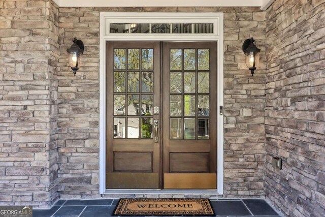 view of exterior entry featuring stone siding and french doors