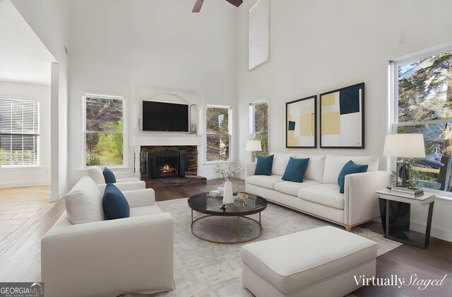 unfurnished living room with a stone fireplace, plenty of natural light, an inviting chandelier, and hardwood / wood-style flooring