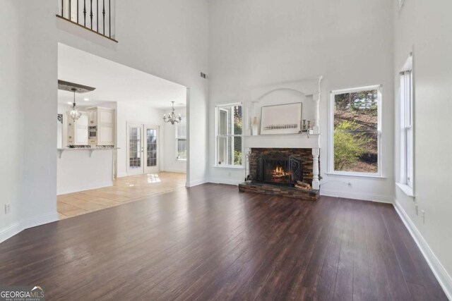 unfurnished living room featuring a stone fireplace, hardwood / wood-style flooring, baseboards, and ceiling fan