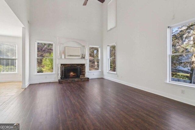 unfurnished living room featuring visible vents, light wood finished floors, baseboards, stairway, and a high ceiling