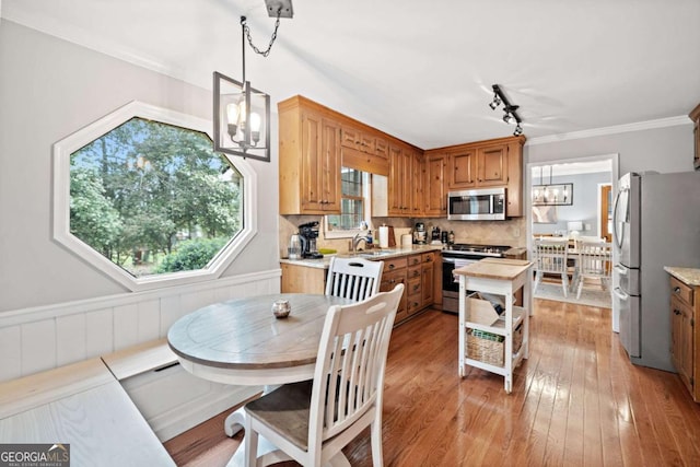 6695 Woodstock Rd, Acworth, GA 30102 - kitchen with crown molding, light wood-type flooring, stainless steel appliances, backsplash, and a notable chandelier
