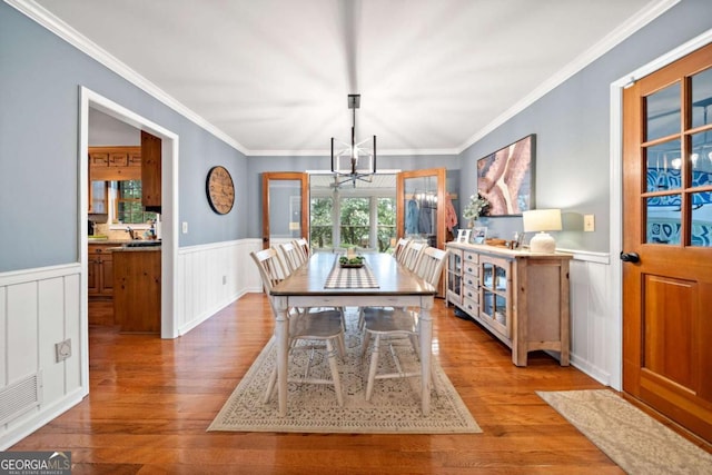 6695 Woodstock Rd, Acworth, GA 30102 - dining space with ornamental molding, a wainscoted wall, a notable chandelier, and wood finished floors