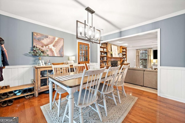 6695 Woodstock Rd, Acworth, GA 30102 - dining room with crown molding, wainscoting, a chandelier, a fireplace, and wood finished floors