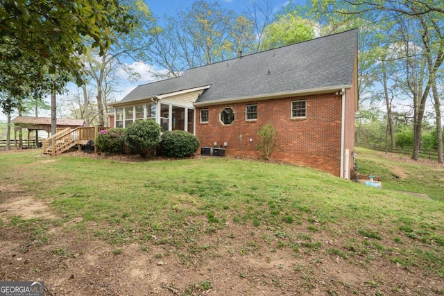 6695 Woodstock Rd, Acworth, GA 30102 - rear view of property featuring a sunroom, fence, brick siding, a shingled roof, and a yard