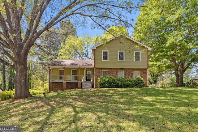tri-level home featuring a porch, a front lawn, and brick siding