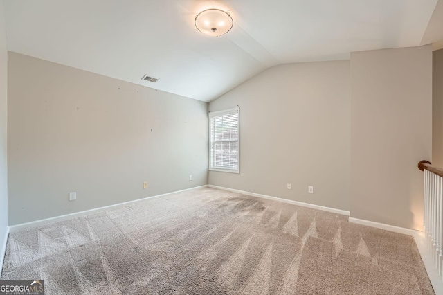 spare room featuring baseboards, vaulted ceiling, visible vents, and carpet floors