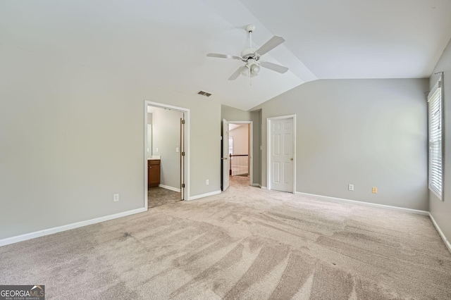 unfurnished bedroom with vaulted ceiling, visible vents, baseboards, light colored carpet, and ensuite bathroom