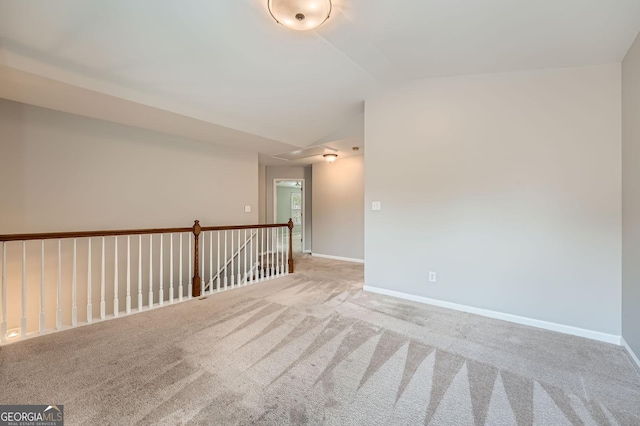 unfurnished room with lofted ceiling, attic access, baseboards, and carpet