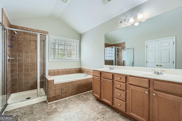 bathroom with a shower stall, vaulted ceiling, a garden tub, a sink, and double vanity