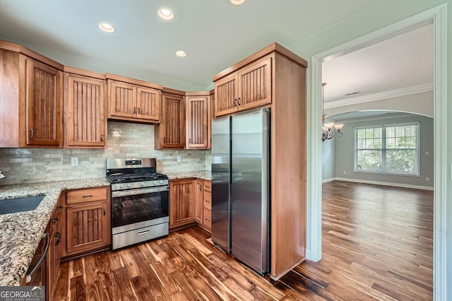 kitchen with stainless steel appliances, a sink, tasteful backsplash, an inviting chandelier, and ornamental molding