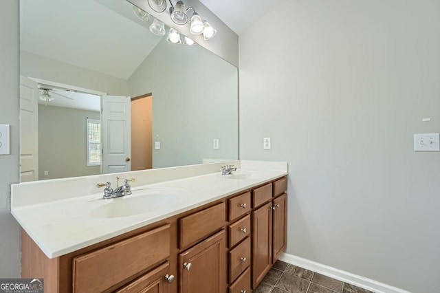 bathroom featuring double vanity, lofted ceiling, baseboards, and a sink