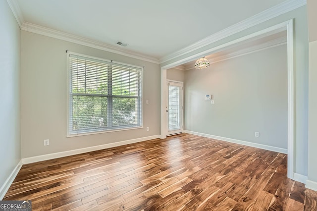 interior space featuring baseboards, wood finished floors, visible vents, and ornamental molding