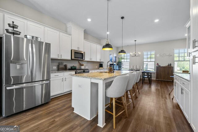 6023 Skellig St, Norcross, GA 30071 - kitchen featuring stainless steel appliances, white cabinets, tasteful backsplash, a center island with sink, and dark wood-style floors