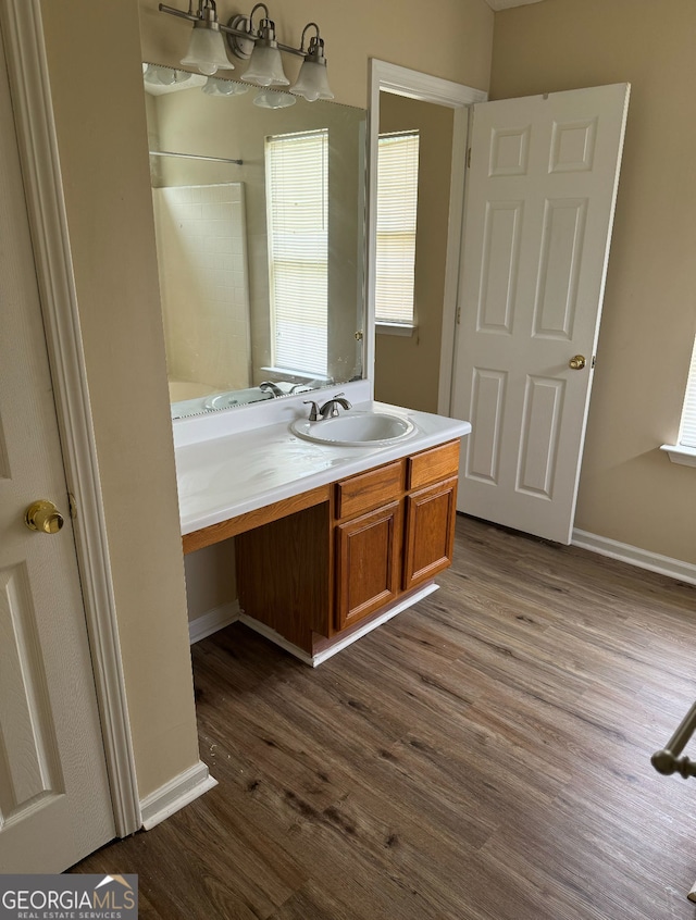 full bath featuring baseboards, a shower, vanity, and wood finished floors