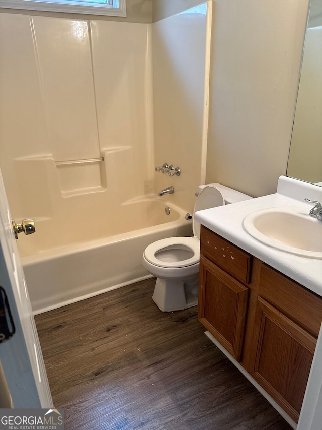 bathroom with toilet, wood finished floors, vanity, and bathtub / shower combination