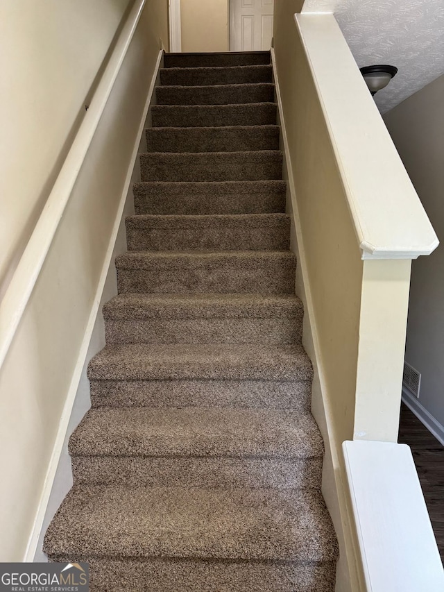 stairs featuring visible vents and a textured ceiling