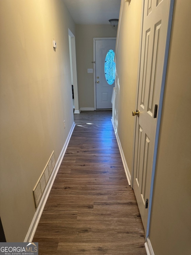 corridor featuring baseboards, dark wood finished floors, and visible vents