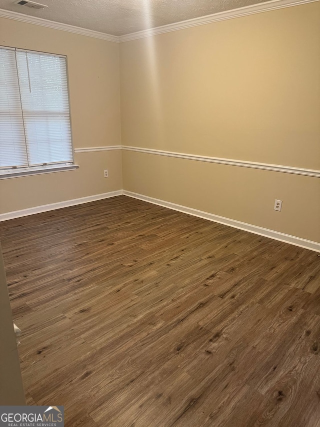 unfurnished room with baseboards, ornamental molding, dark wood-style floors, a textured ceiling, and visible vents