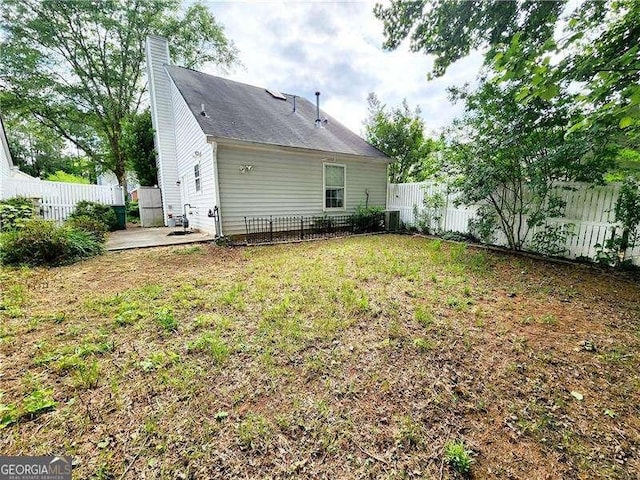 645 Crossbridge Aly, Johns Creek, GA 30022 - back of property with a patio, a fenced backyard, a chimney, and a lawn