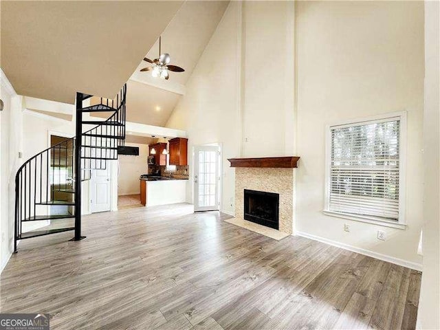 645 Crossbridge Aly, Johns Creek, GA 30022 - unfurnished living room featuring a ceiling fan, stairs, a fireplace with flush hearth, light wood-style floors, and high vaulted ceiling