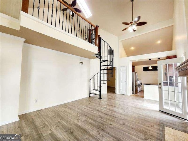 645 Crossbridge Aly, Johns Creek, GA 30022 - unfurnished living room featuring baseboards, stairway, a high ceiling, ceiling fan, and wood finished floors