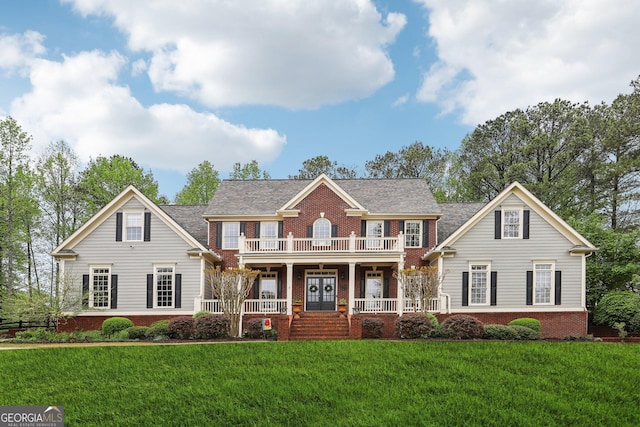 view of front of house featuring a porch, a balcony, a front yard, and brick siding